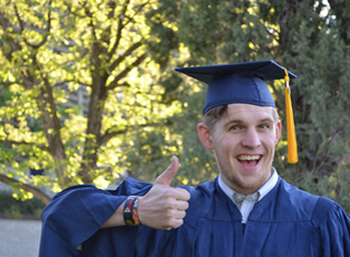 Man in cap and gown giving thumbs up